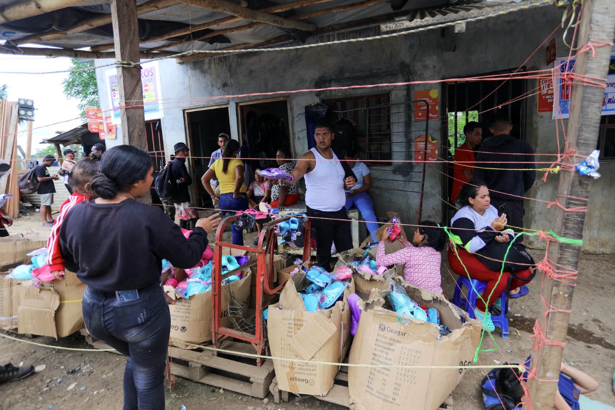 2023年9月23日，巴拿馬達(dá)連省拉哈斯布蘭卡斯移民接待站等待前往美國的移民，一名男子將捐贈的鞋子遞給一名懷著嬰兒的婦女。