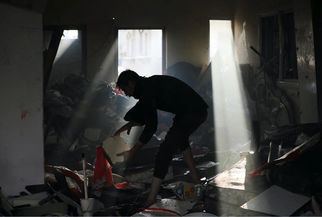 2024年1月3日，巴勒斯坦人在以色列襲擊加沙地帶中部馬加齊難民營(yíng)的現(xiàn)場(chǎng)撿拾殘骸。