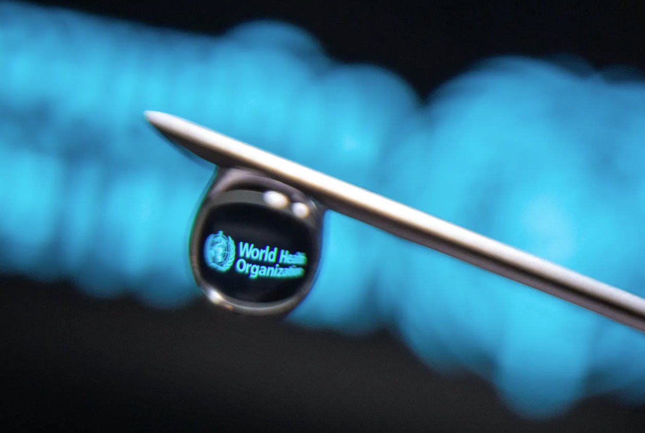 在這張拍攝于2021年3月16日的插圖照片中，世界衛(wèi)生組織的徽標反映在注射器針頭上的一滴水滴中