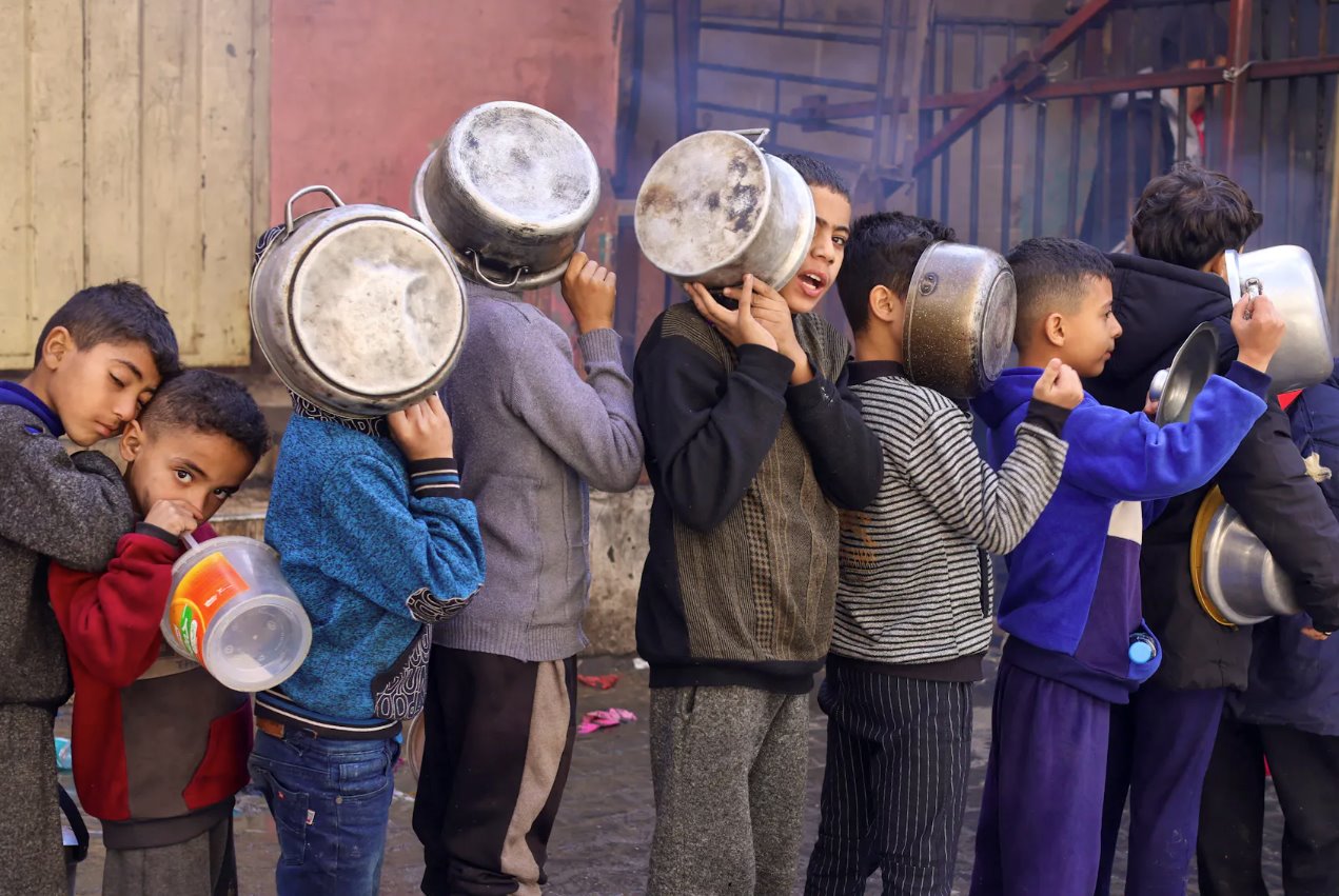 2023年12月14日，在加沙地帶南部的拉法，隨著以色列和哈馬斯之間的沖突持續(xù)，巴勒斯坦兒童拎著鍋排隊(duì)領(lǐng)取慈善廚房烹制的食物，沖突繼續(xù)導(dǎo)致糧食供應(yīng)短缺。