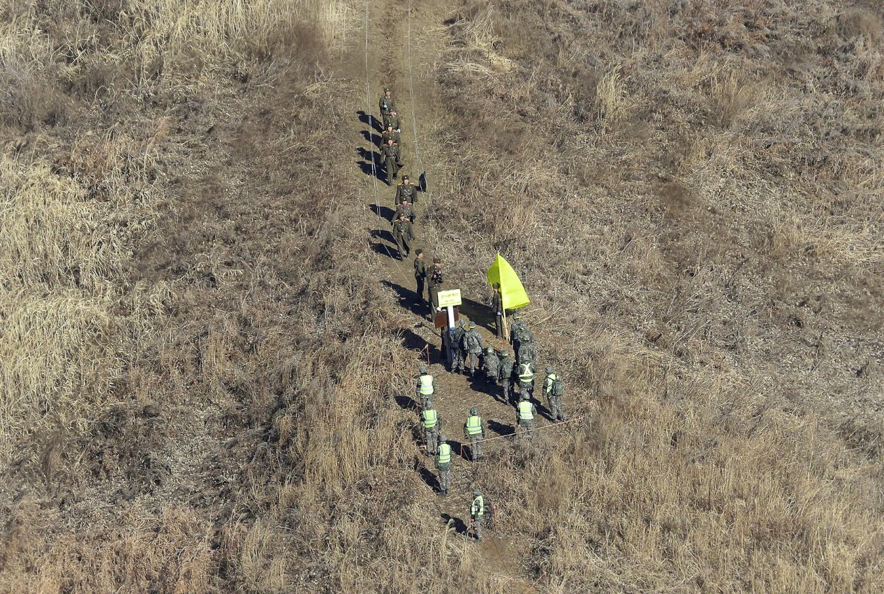 2018年12月12日，朝鮮軍隊士兵（上）越過非軍事區(qū)(DMZ)內(nèi)的軍事分界線，檢查已拆除的韓國哨所，韓國軍隊士兵則在鐵原的朝韓邊界中部地區(qū)觀看。