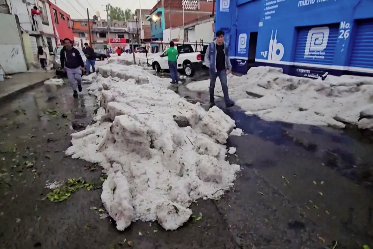 2024年5月24日，墨西哥普埃布拉，熱浪中的冰雹過后，人們在厚冰旁行走。