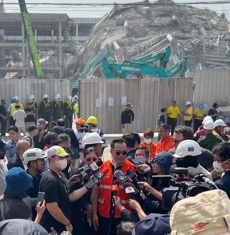 泰國(guó)副總理站在倒塌建筑的廢墟前，被記者包圍。