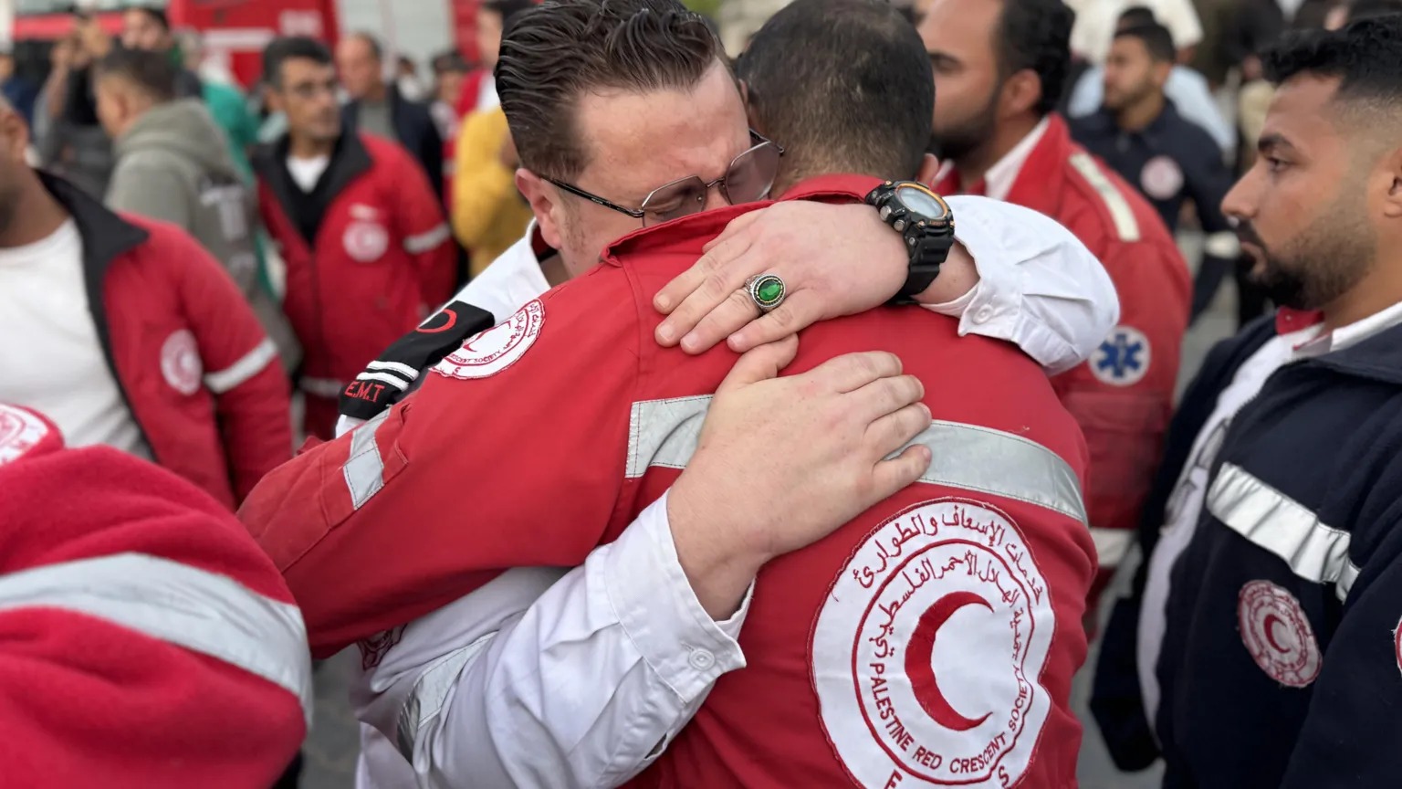 巴勒斯坦紅新月會(huì)的員工們擁抱在一起，看著同事的遺體被送往加沙南部汗尤尼斯的一家醫(yī)療機(jī)構(gòu)